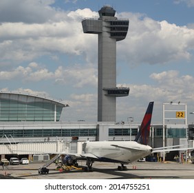 NEW YORK - May 16, 2019: Air Traffic Control Tower And Delta Airlines Plane On Tarmac At Terminal 4 At JFK International Airport. JFK Is One Of The Biggest Airports In The World With 4 Runways 