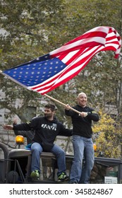 NEW YORK - NOV 25 2015: A Member Of Iran And Afghanistan Veterans Of America (IAVA) Waves A Large American Flag While Standing On The Roof Of A Military Truck At The Americas Parade On Veterans Day.