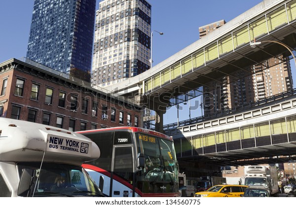 NEW YORK - NOVEMBER 6th: Wide angle horizontal view\
of two buses amongst the traffic at 9th avenue, with the Port\
Authority bus terminal in the background on November 6 2012 in New\
York, New York.