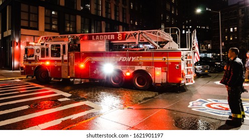 New York, NY - 1/30/19: FDNY Firetruck Backing Into The Ghostbusters Firehouse Hook & Ladder Company 8 And A Fireman Standing At Night Time In Manhattan, New York City, NY