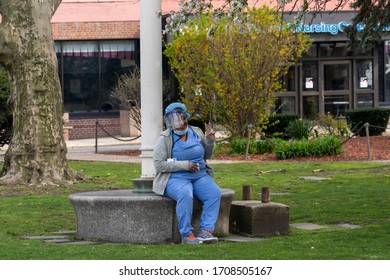 NEW YORK, NY - APRIL 19, 2020: A Nurse Wearing A Personal Protective Equipment (PPE) Takes A Break Outside The Coler Hospital Campus On Roosevelt Island Amid The Covid-19 Pandemic.