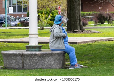 NEW YORK, NY - APRIL 19, 2020: A Nurse Wearing A Personal Protective Equipment (PPE) Takes A Break Outside The Coler Hospital Campus On Roosevelt Island Amid The Covid-19 Pandemic.