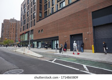 NEW YORK, NY - APRIL 20, 2020: New Yorkers Wait In Long Lines 6 Feet Apart To Get Into A Midtown Grocery Store Due To COVID19. 