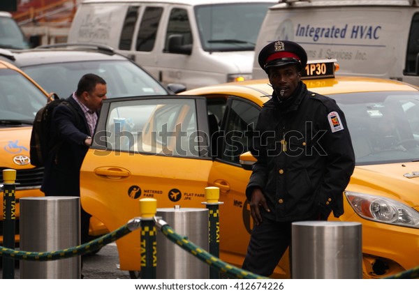 New York, NY - April 28, 2016: A\
Manhattan commuter enters a yellow taxi after a 34th street\
concierge hails yellow taxis. A controversy over competition from\
the Uber transportation technology\
app.