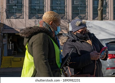 NEW YORK, NY – JANUARY 10: A Worker Verifies Eligibility And Registration Of A Woman In Line To Get COVID-19 Vaccine At NYC Health Department Vaccine Hub At Hillcrest High School In Queens.