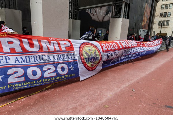 New York, NY - October 25, 2020: Pro President\
Trump re-election supporters march along 5th avenue with caravan of\
cars and huge Trump flag