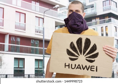 New York, NY / United States - Jul 12 2019: China Spying Via Huawei. Ban Huawei Protest. Man With Covered Face Holds Banner With Drawn Black Huawei Logo. Sanctions