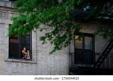 New York, NY / United States - May 16th 2020: A woman shakes a maraca out her window to thank healthcare workers during the COVID-19 pandemic in Washington Heights, Manhattan, New York City. 