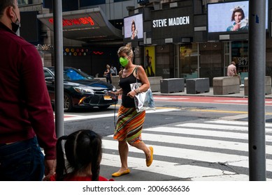 New York, NY United States July 9th 2021: A Woman In A Lime Green N95 Mask Crosses The Street At A Crosswalk In Times Square, Manhattan, New York City. 