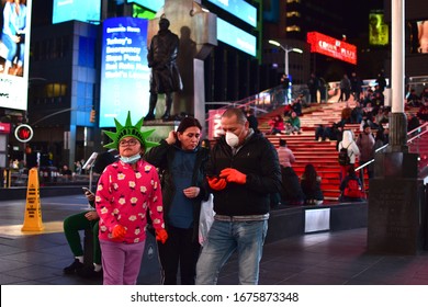 New York, NY, US - March 17, 2020: A Family In Face Masks And Rubber Gloves, Including A Girl Wearing A Statue Of Liberty Crown, Visits An Emptier-than-usual Times Square Amid The Covid-19 Pandemic.