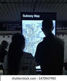 New York, NY/ USA- 8-1-19: Couple Looking At Subway Information Digital Screen For Directions On NYC Subway Map MTA Train Station