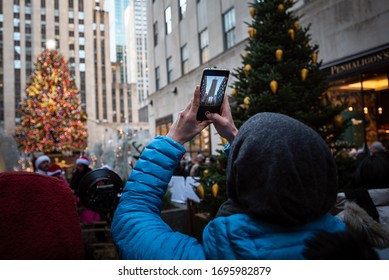 NEW YORK, NY, USA- DECEMBER 27, 2019 Tourist Taking Photos Of The Rockefeller Christmas Tree With His Smartphone