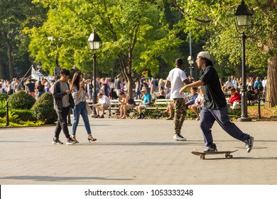 New York, NYC, USA- August 27, 2017: People relaxing in the Washington Square Park in summer, sunny day. Bryant Park, privately managed public park located in the New York City borough of Manhattan.