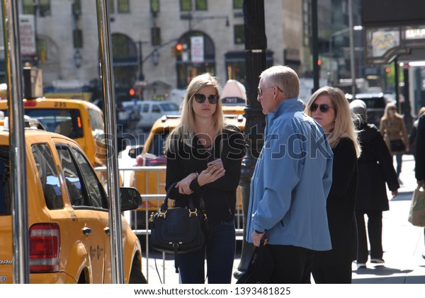 New York, NY/United States-\
04/23/2019: A wealthy family waits for a taxi outside a luxury\
hotel. 