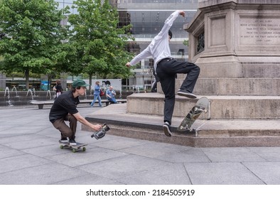 New York, NYUSA - 05-07-2016: Young Filmmaker Video Tapes Skateboarder At A Park In Manhattan.