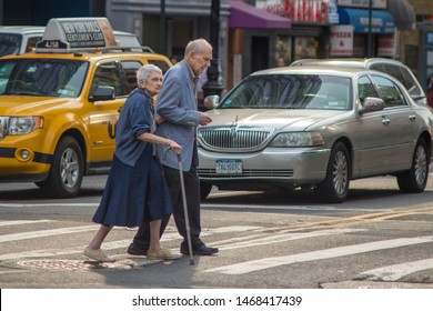 New York, NY/USA - May 5, 2015: Two Elderly Senior Citizens, One With A Cane, Cross Busy New York City Street.