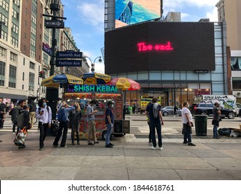 NEW YORK - October 24, 2020: People waiting on line at Madison Square garden for the 1st day of early voting. Waiting by street vender with a billboard reading "The End"
