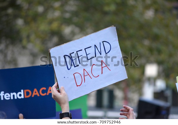 New York, New York - September 5, 2017: People\
carrying signs protesting President Trump\'s decision to repeal the\
Deferred Action for Childhood Arrivals (DACA) policy in Lower\
Manhattan.