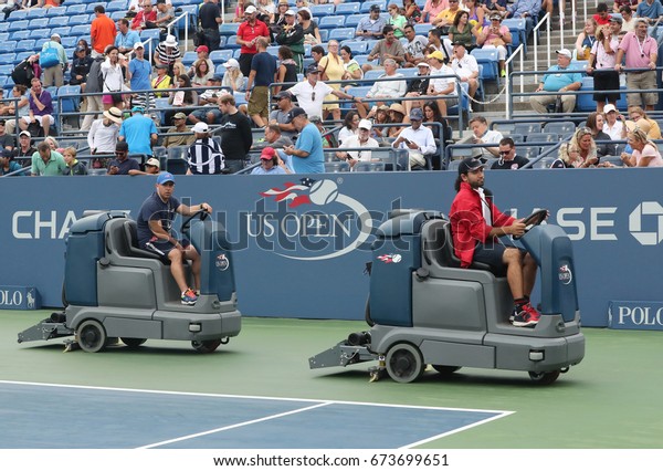 NEW YORK - SEPTEMBER\
6, 2016: US Open cleaning crew drying tennis court after rain delay\
at Louis Armstrong Stadium at Billie Jean King National Tennis\
Center in New York