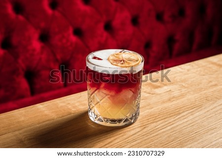 New York sour or Continental sour cocktail with bourbon or whisky garnished with dried lemon wheel at the wooden table at bar or restaurant, horizontal photo