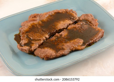 New York Strip Steak With Garlic Brown Sauce On Blue Serving Plate