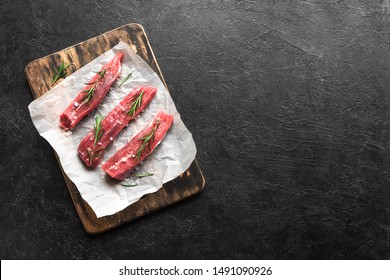 New York Strip Steak With Salt And Rosemary On Black Background, Top View, Copy Space. Uncooked Raw Beef Strip Steaks.