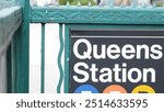 New York subway sign, Queens underground metro station. Metropolitan entrance fence, public transport exit. Long Island city street, NYC United States. Navigation text on signboard. Pedestrians people