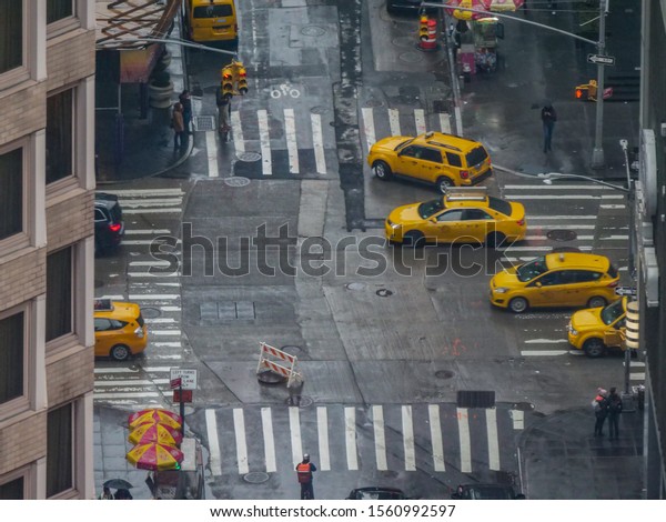 NEW YORK, UNITED STATES OF AMERICA, OCTOBER\
2018: CLOSE UP: Yellow cabs and cars drive through the wet old\
streets of New York City on a cold and rainy day. People cross the\
street in Manhattan.