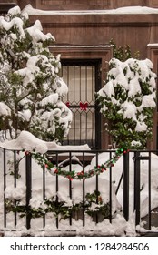 New York, Upper East Side After A Snowstorm, Detail Of Wrought Iron Fence With Snow And Christmas Greens In Front Of Brownstone