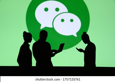 NEW YORK, USA, 25. MAY 2020: WeChat Chinese messaging, social media and mobile payment app Group of business people chat on mobile phone and laptop. Company logo on screen in background