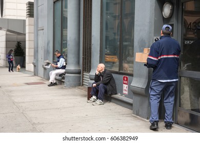 NEW YORK, USA - Apr 28, 2016: Delivery Service Worker Delivers Package To Addressee. Two Men Are Resting Sitting On The Porch. One Of Them Is Reading A Newspaper. A Girl Is Walking With A Dog