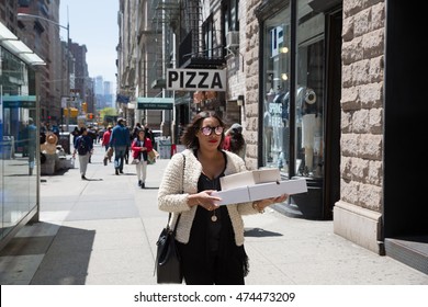 NEW YORK, USA - Apr 30, 2016: Fifth Avenue. Woman Carrying A Pizza Box. Manhattan Street Scene. The Americans On The Streets Of New York City