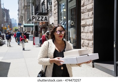 NEW YORK, USA - Apr 30, 2016: Fifth Avenue. Woman Carrying A Pizza Box. Manhattan Street Scene. The Americans On The Streets Of New York City