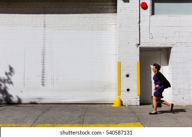 NEW YORK, USA - Apr 30, 2016: Manhattan Street Scene. Woman In A Hurry About Their Business Against A White Brick Wall