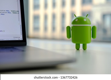 New York, USA - April 10, 2019 - Google Android figure standing on desk near laptop computer