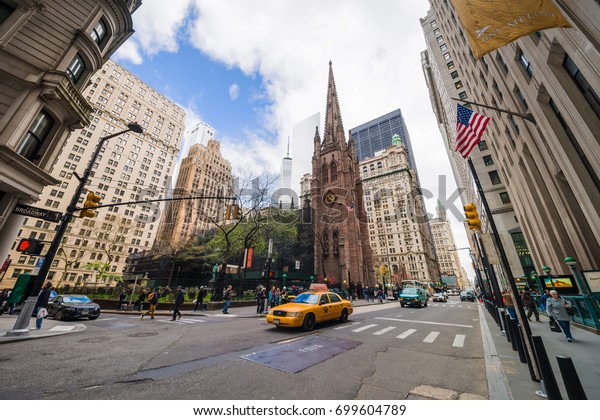 New\
York, USA - April 24, 2015: Trinity Church in Lower Manhattan and\
street with tourists and traffic, New York, NYC, USA. It is a\
historic parish church near Wall Street and\
Broadway.