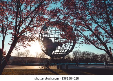 New York, USA - April 3, 2019 - Unisphere monument in Flushing Meadows–Corona Park, Queens, New York City in spring through cherry tree pink blossoms