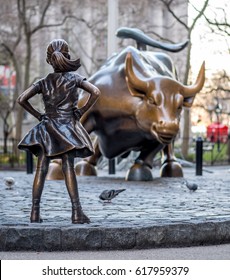 New York, USA - April 9, 2017 - "The Fearless Girl" statue facing Charging Bull in Lower Manhattan, New York City