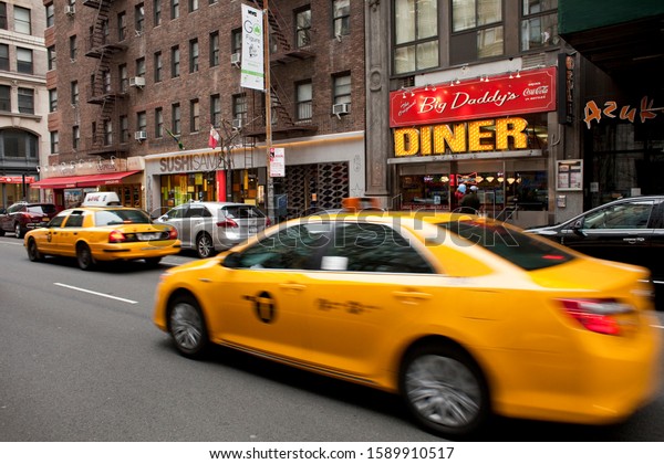 New\
York, USA – December 8, 2013: Horizontal view of two yellow cabs\
passing by Big Daddy’s Diner in Park Ave,\
Manhattan