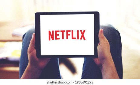 New York, USA - February 20, 2021: Netflix app logo on the tablet screen, selective focus on person's hands holding a mobile device while watching videos online at home.