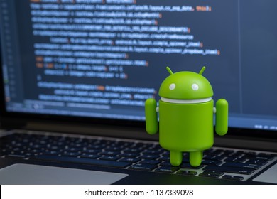 New York, USA - July 2, 2018 - Google Android figure standing on laptop keyboard with code in background