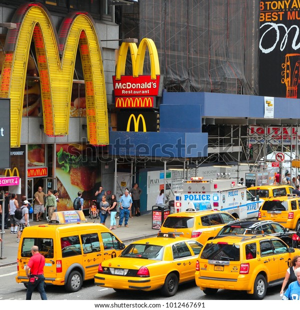 NEW YORK, USA - JULY 3, 2013: Taxis drive along\
Times Square in New York. Times Square is one of most recognized\
landmarks in the world. More than 300,000 people pass through Times\
Square daily.