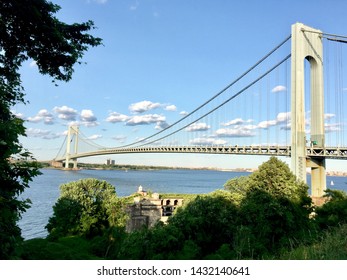 New York, New York, USA - June 22, 2019: The Verrazzano-Narrows Bridge connecting the boroughs of Brooklyn and Staten Island crosses The Narrows with Battery Weed on Fort Wadsworth in the foreground.