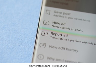 New york, USA - June 28 2021: Report scam ad in facebook post on smartphone screen close up