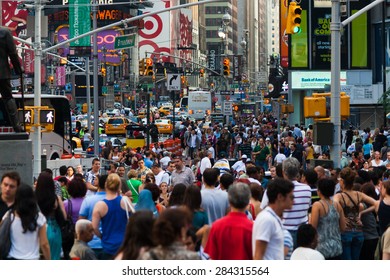 New York, USA - June 30, 2009: A Crowd Moves Through Times Square, Next To The Avenue Of Broadway Full Of Traffic And Under A Maze Of Lights And Advertisements.