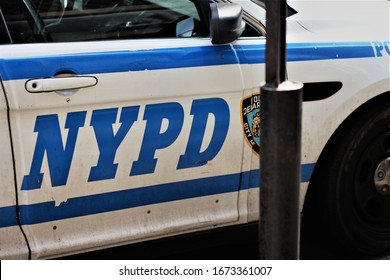 New York, USA / March, 2020 / An NYPD Police Cruiser Parked Up On The Side Street. No Officer At The Wheel. Clear Focus On The NYPD Badge And Decal. Showing Its Scarred Body From Impacts And Life.