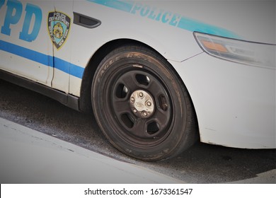 New York, USA / March, 2020 / An NYPD Police Cruiser Parked Up On The Side Street. No Officer At The Wheel. Clear Focus On The NYPD Badge And Decal. Showing Its Rugged Steel Wheels And Tyres.
