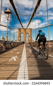 New York, USA - March 9, 2022: Cyclist Riding On The Bike Path Along Brooklyn Bridge