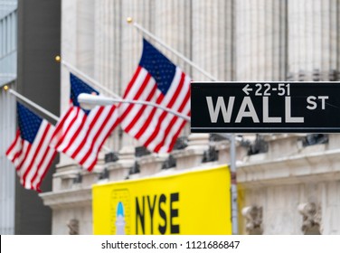 New York, USA - May 14, 2018: Wall Street sign near New York Stock Exchange with flags of the United States. It is the world's most significant financial center.