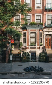 New York, USA - May 30, 2018: Facade Of A Typical New York House With A Stoop, Rubbish In Black Bins In Front Of It. The City Generates More Than 11,000 Tons Of Residential Garbage Daily.
